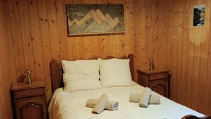 Una habitación con paneles de madera, una cama, dos mesitas de noche, una lámpara y un cuadro en la pared.