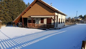 Un edificio cubierto de nieve con un porche, un patio cercado y un cielo despejado.