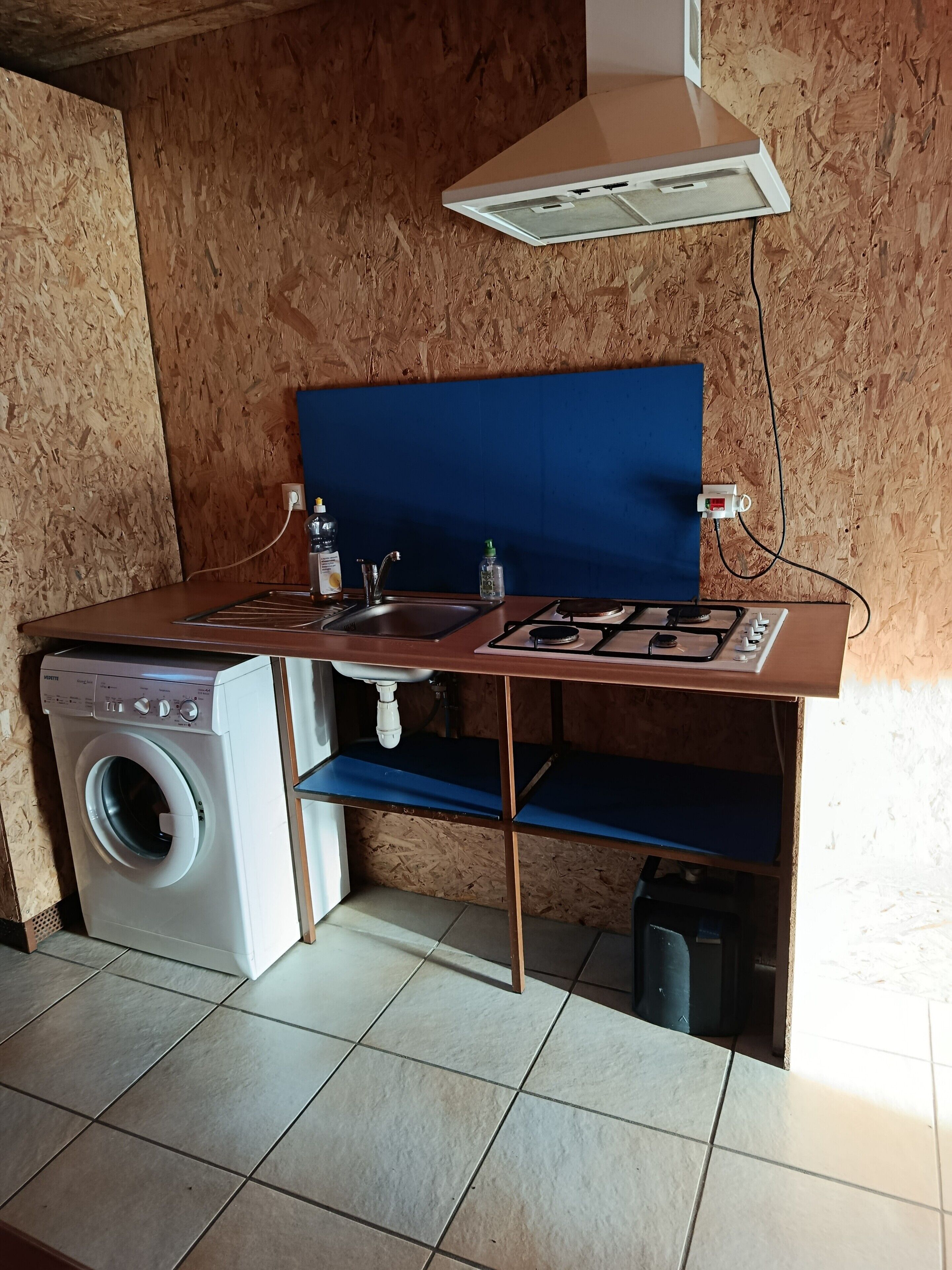 Una cocina compacta con lavadora, lavamanos y estufa.