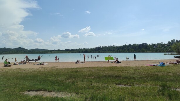 Una playa con gente, un bote y un lago.