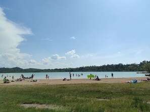 A beach with people, a boat, and a lake. - Chalet 'nature près du lac de Clairvaux' with Garden, Tranquility, Pets Allowed (Pont-de-Poitte)