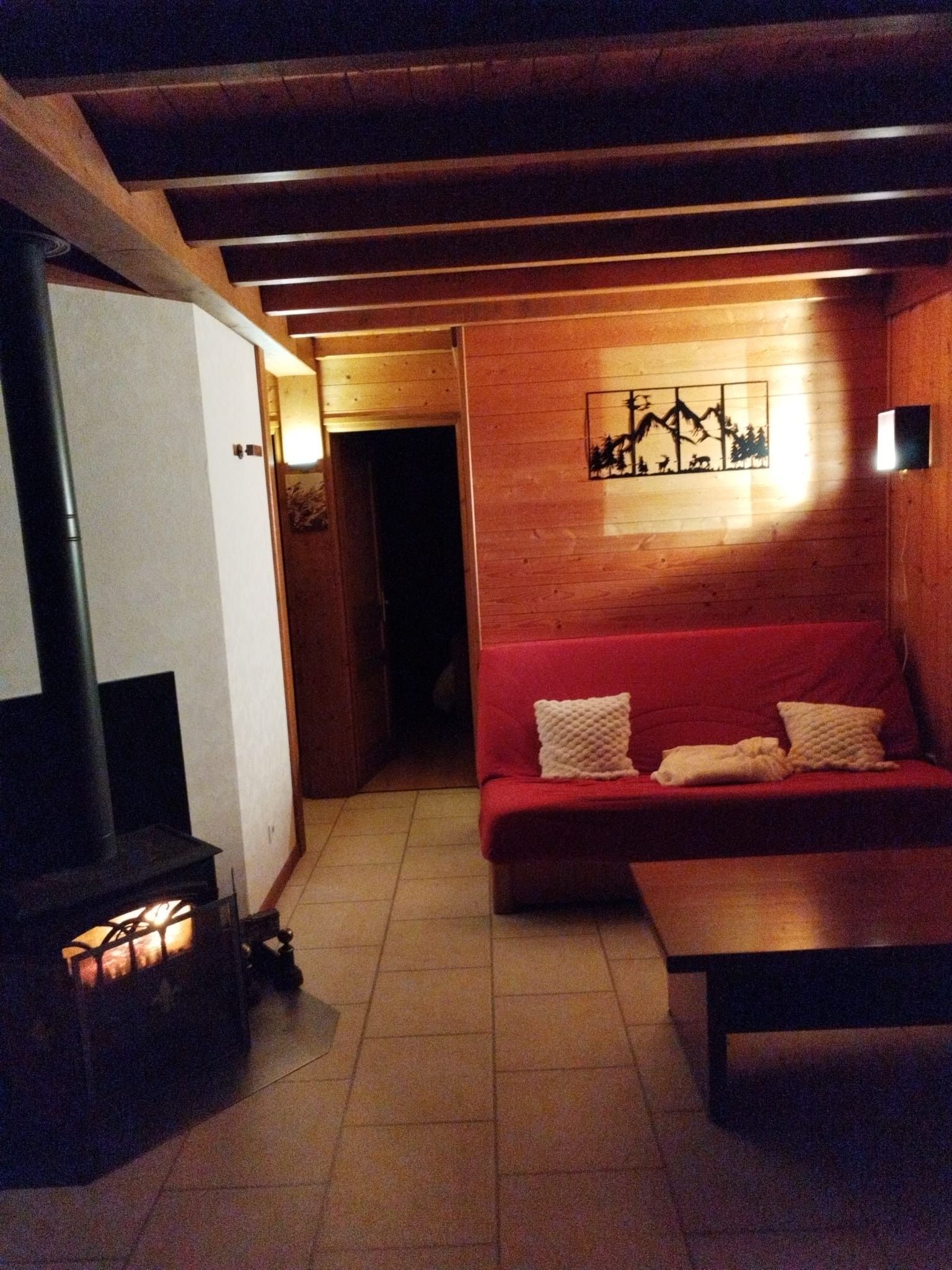 Una sala de estar acogedora con un sofá rojo, una chimenea y una obra de arte colgada en la pared.