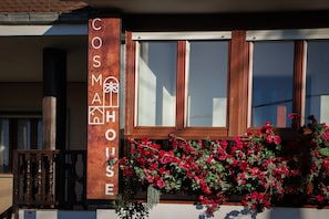 A building with a sign reading 'COSM HOUSE' and a window with red flowers.