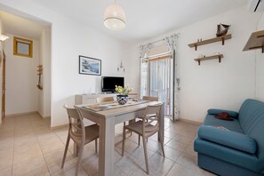 Un coin repas avec une table et des chaises, un téléviseur et une fenêtre avec des rideaux.