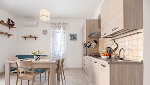 A modern kitchen with wooden cabinets, a dining table with chairs, and a pendant light. - Casa Jessica – Your Stay Between the Sea, Relaxation, and Authentic Sicily (Balestrate)