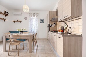 Une cuisine moderne avec des meubles en bois, une table à manger avec des chaises et un luminaire suspendu.