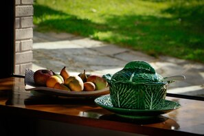 Una mesa con un frutero y una jarra de cerámica verde.