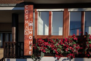 A building with a sign reading 'COSM HOUSE' and a window with red flowers.