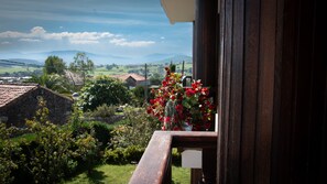 A balcony with a view of a rural landscape, including houses and hills.