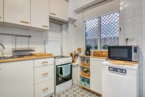 A modern kitchen with white cabinetry, a stove, a dishwasher, and a microwave.