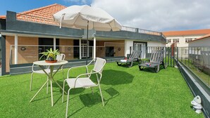A patio with artificial grass, a table with chairs, and an umbrella.