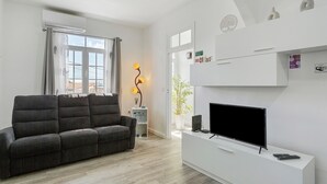 A modern living room with a sofa, TV, and a lamp.