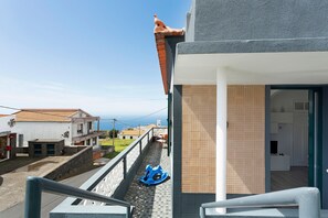 Un balcón con un tobogán azul, vista al mar y un edificio con fachada de azulejos.