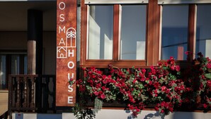 Ein Gebäude mit einem Schild, auf dem 'COSM HOUSE' steht, und einem Fenster mit roten Blumen.