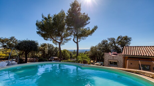 Une piscine offrant une vue dégagée sur le paysage environnant et un bâtiment doté d’un toit en tuiles.