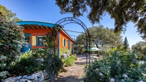 Une maison aux couleurs vives, avec un chemin de jardin qui mène à une arche en métal.