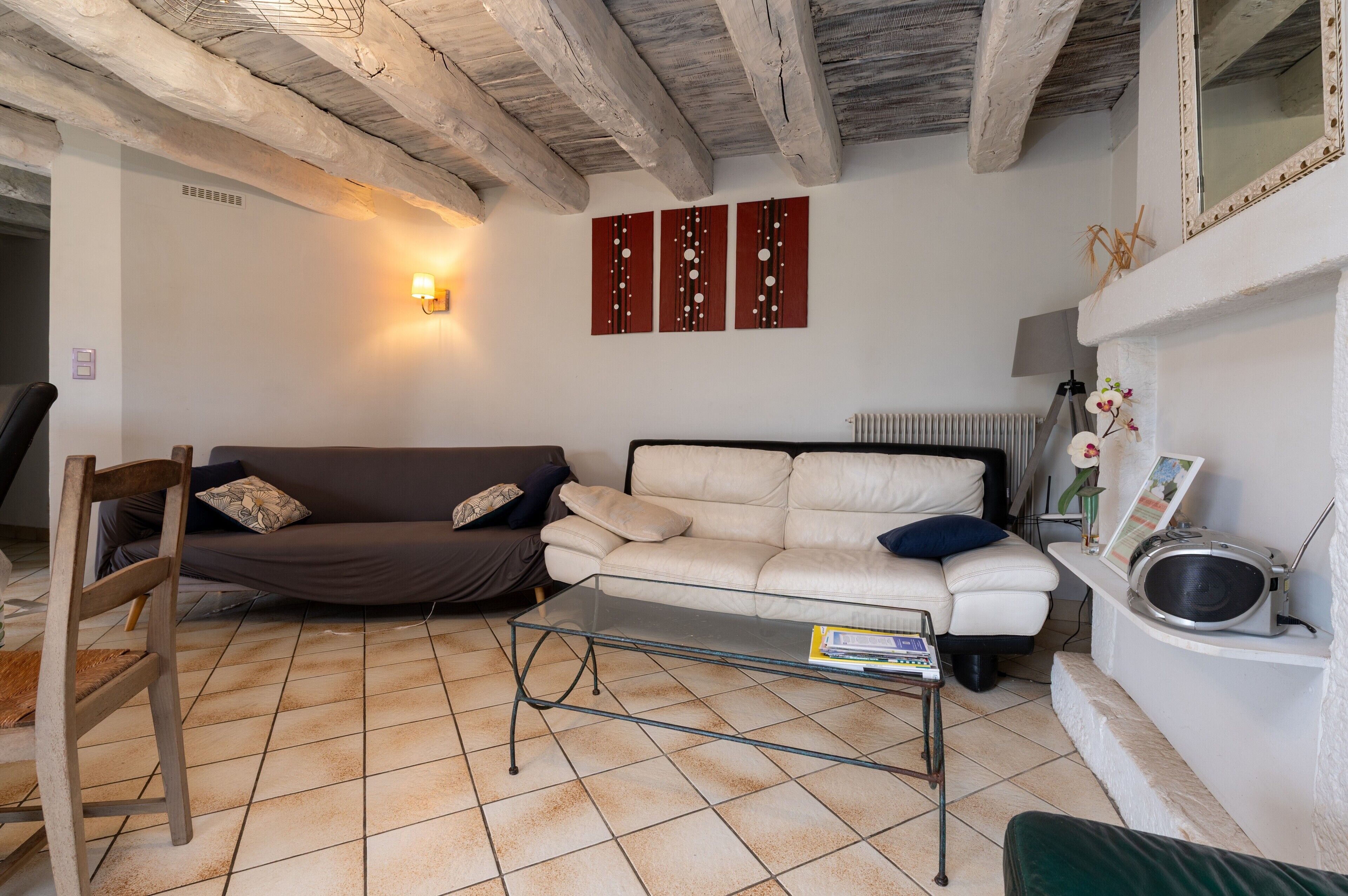 Een woonkamer met een glazen salontafel, twee banken, een houten stoel, een open haard en een wandlamp.