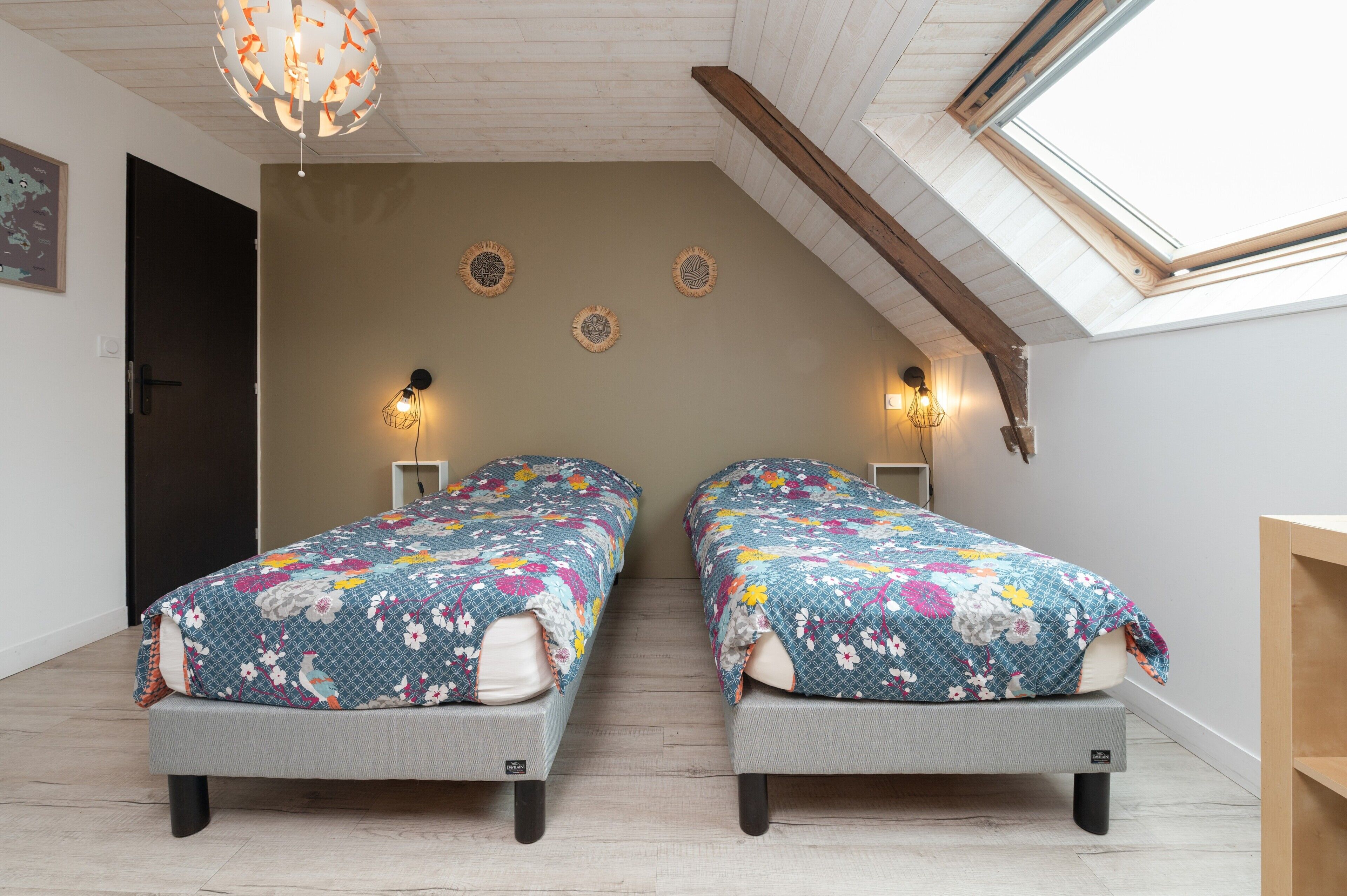 A room with two beds, a skylight, and a wooden ceiling.