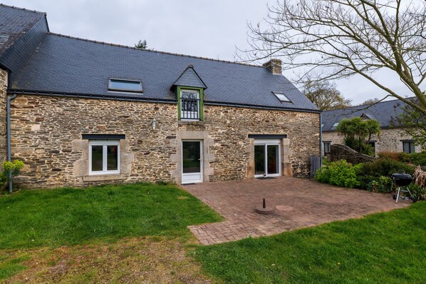 A stone building with a sloped roof, a small window, and a door.