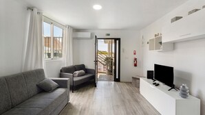 A modern living room with a sofa, a TV, and a console table. - Casa Pereira 2: Perfect for Relaxing and Enjoying Beautiful Sunsets (Ponta do Pargo)