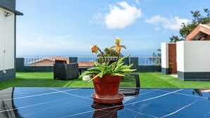 A solar-powered table with a potted plant in the center, set against a clear sky and a view of the sea. - Casa Pereira 2: Perfect for Relaxing and Enjoying Beautiful Sunsets (Ponta do Pargo)
