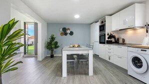 A modern kitchen with white cabinets, a built-in oven, and a washing machine. - Casa Pereira 2: Perfect for Relaxing and Enjoying Beautiful Sunsets (Ponta do Pargo)