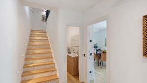 En modern inredning med en trappa i marmor, ett köksområde och en matplats.