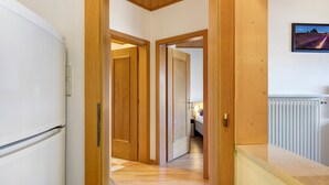 Un pasillo con puertas de madera, un radiador blanco y un cuadro en la pared.