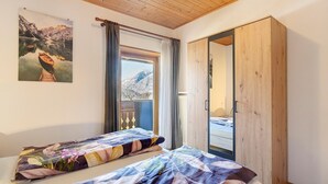 Un dormitorio con dos camas, un armario de madera, una ventana con cortinas y un cuadro en la pared.