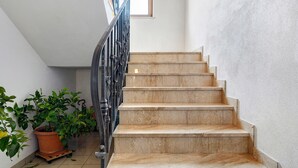Una escalera con peldaños de mármol y barandilla de metal, que conduce a una plataforma.