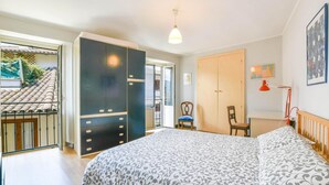 Een slaapkamer met een bed, kast, stoel en uitzicht op het balkon.