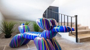 A colorful, striped sculpture in a courtyard with a staircase and potted plants. - Villa with swimming pool, sauna, fitness, sea view (Biot)