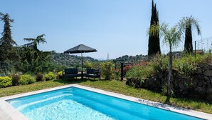 A swimming pool with a stone wall and greenery. - Villa with swimming pool, sauna, fitness, sea view (Biot)