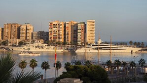 Eine Marina mit Yachten, einer Brücke und hoch aufragenden Gebäuden im Hintergrund.