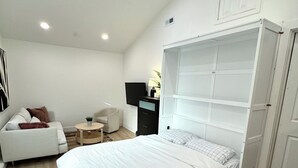 A bedroom with a large bed, a sofa, a TV, and a wardrobe.
