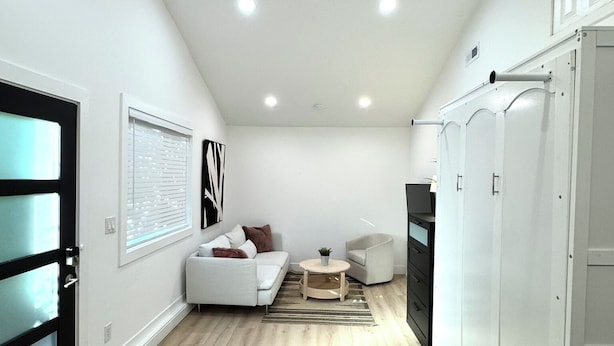 A modern, well-lit living room with a sofa, a coffee table, and a glass table with a plant.