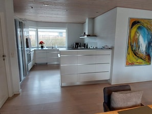 A modern kitchen with white cabinetry, a large island, and a window providing natural light.