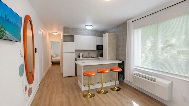 A modern kitchen with a central island, white cabinets, and a large window with blinds. - Miami Beach Escape Delightful 1 Bedroom  (Miami Beach)