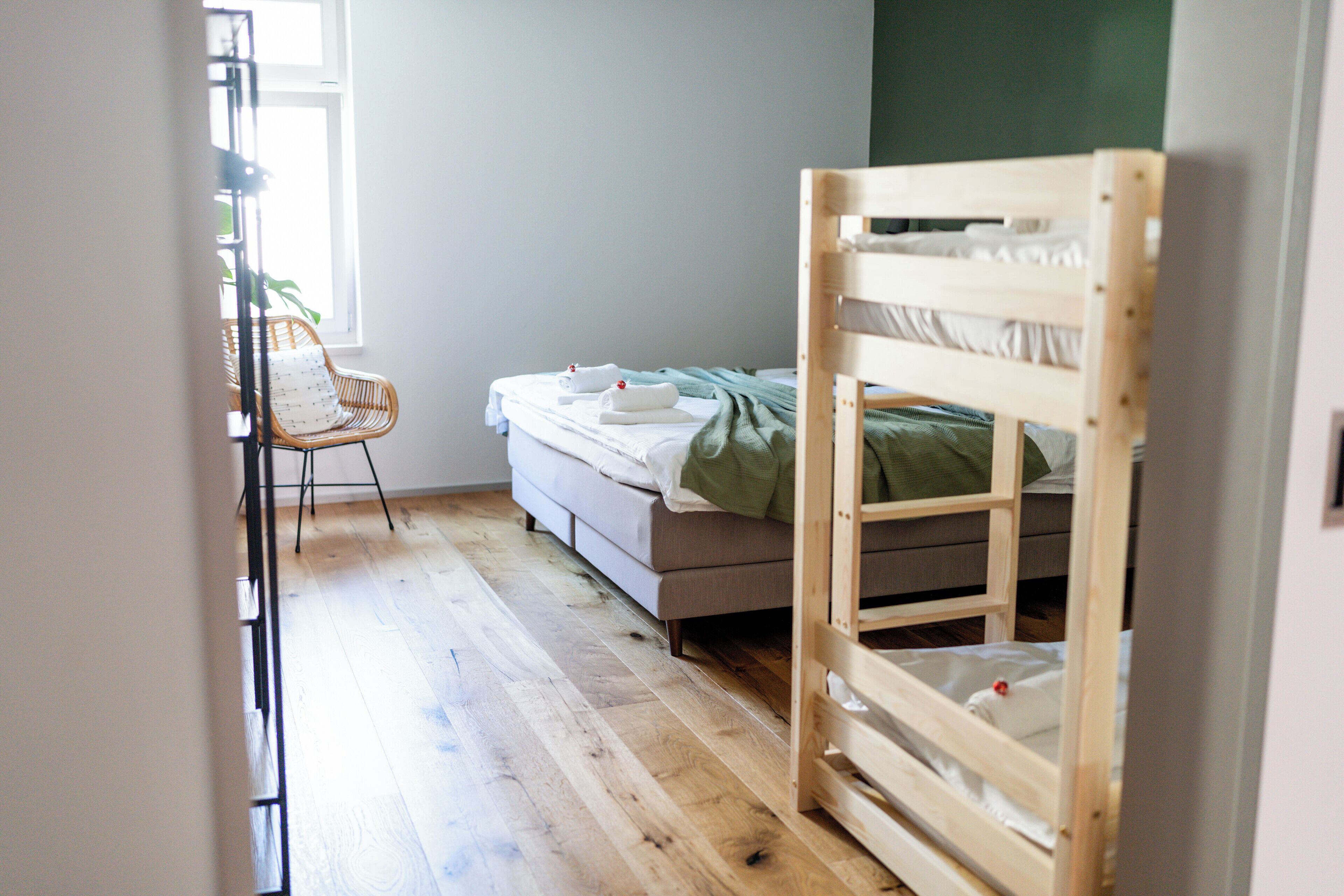 Een kamer met een stapelbed, een stoel en een raam.
