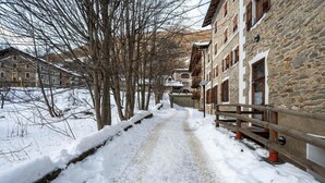 Un sendero cubierto de nieve que lleva a un edificio de piedra con múltiples ventanas y balcones.