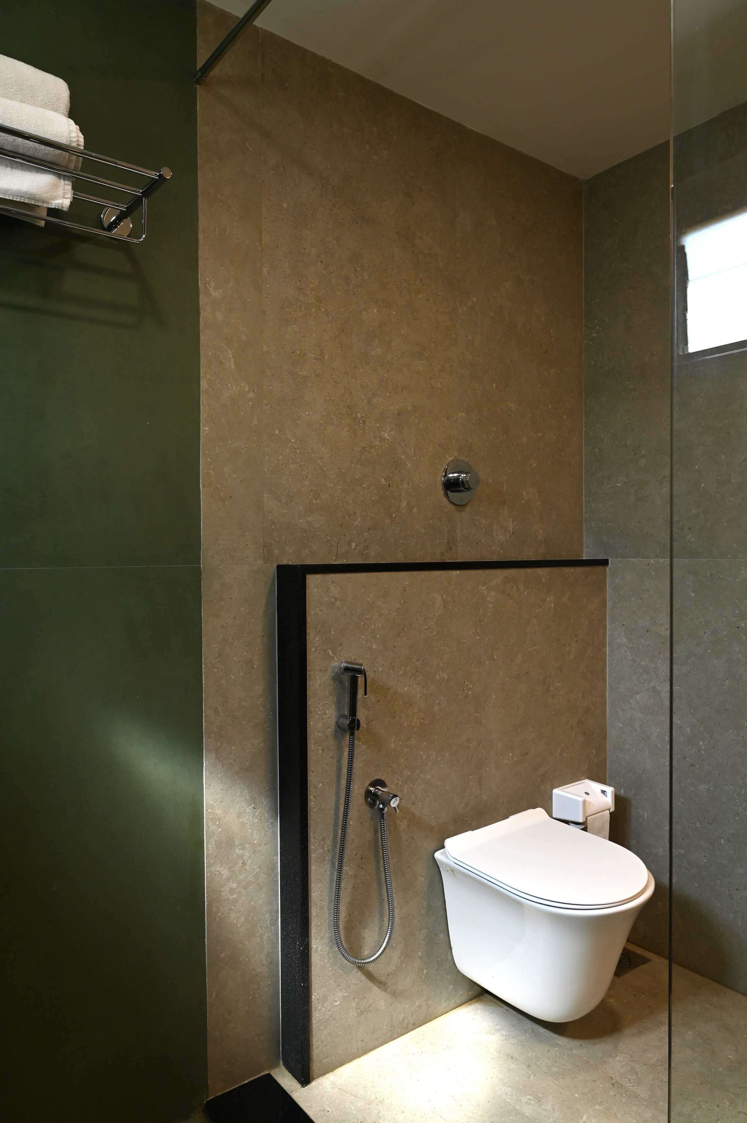 Un baño moderno con ducha de mampara de vidrio, inodoro blanco y barra para toallas.
