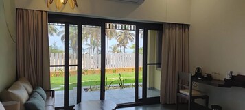 Una habitación con una puerta corrediza de vidrio que da a un patio trasero con cerca blanca y palmeras.