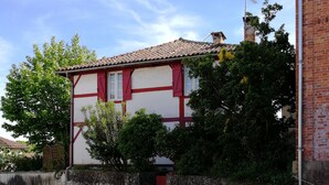 A two-story building with a red and white facade, a tiled roof, and a chimney. - In the heart of the village, 70 m2 Landes house ideal for a family of 4 people (Léon)