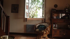 A room with a wicker chair near a window, a wooden cabinet, and a tiled floor. - In the heart of the village, 70 m2 Landes house ideal for a family of 4 people (Léon)