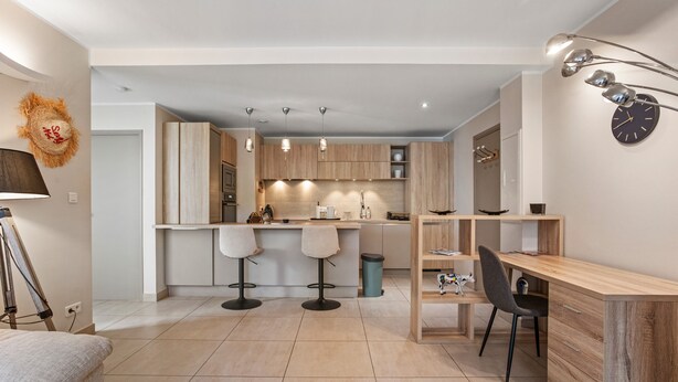 Eine moderne Küche mit Holzschränken, einer Bar und einem Essbereich mit Holztisch und Stühlen.