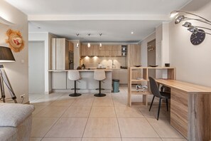 A modern kitchen with wooden cabinets, a bar area, and a dining space with a wooden table and chairs. - Apartment 'Moderne St Tropez' (Saint-Tropez)