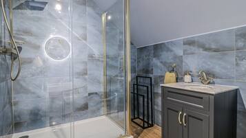 Een moderne badkamer met een douchecabine van glas, een wastafelmeubel en marmeren tegels.