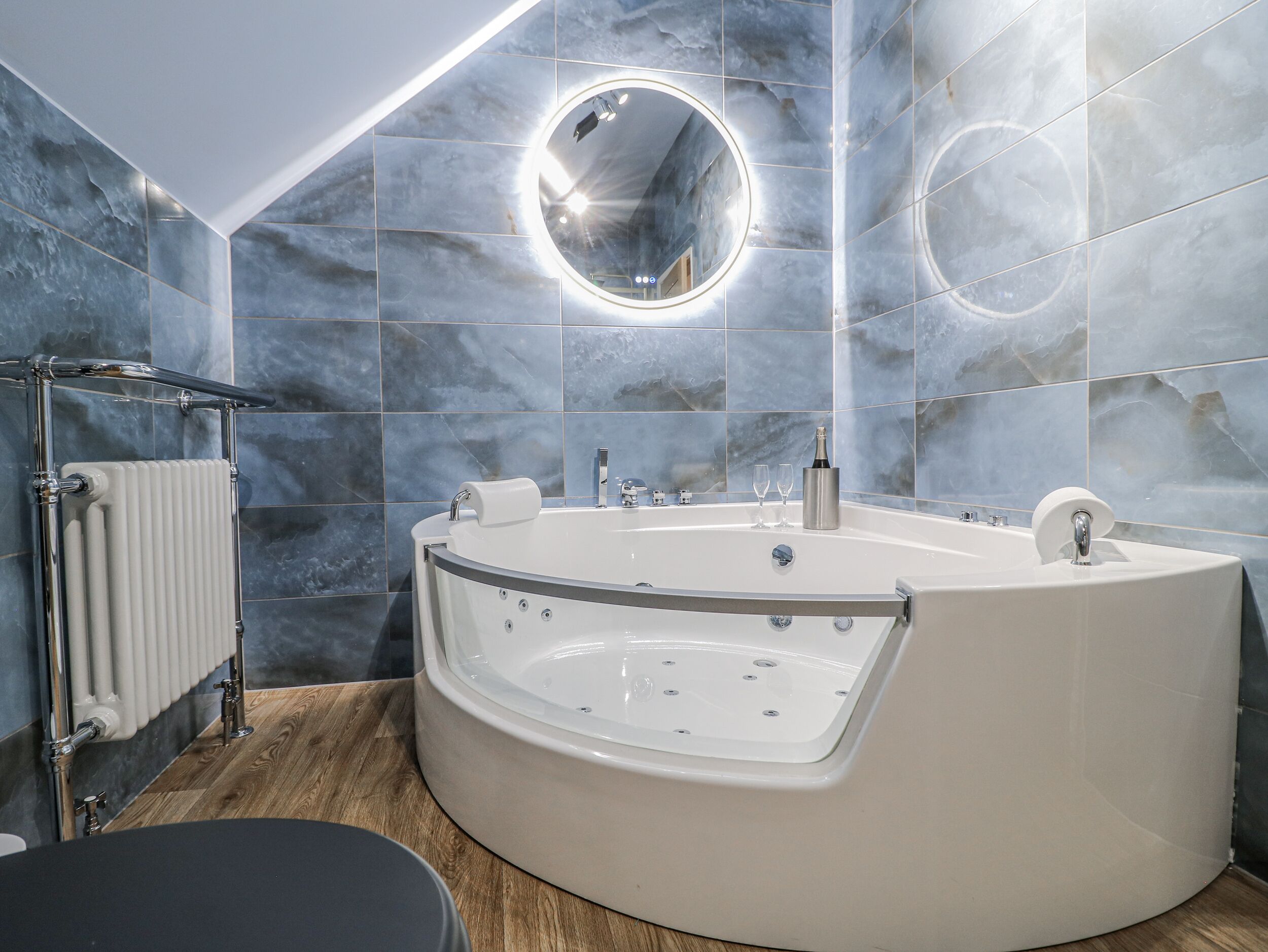 A modern bathroom with a freestanding bathtub, a round mirror, and a towel rack.