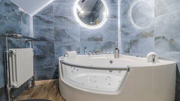 A modern bathroom with a freestanding bathtub, a round mirror, and a towel rack.