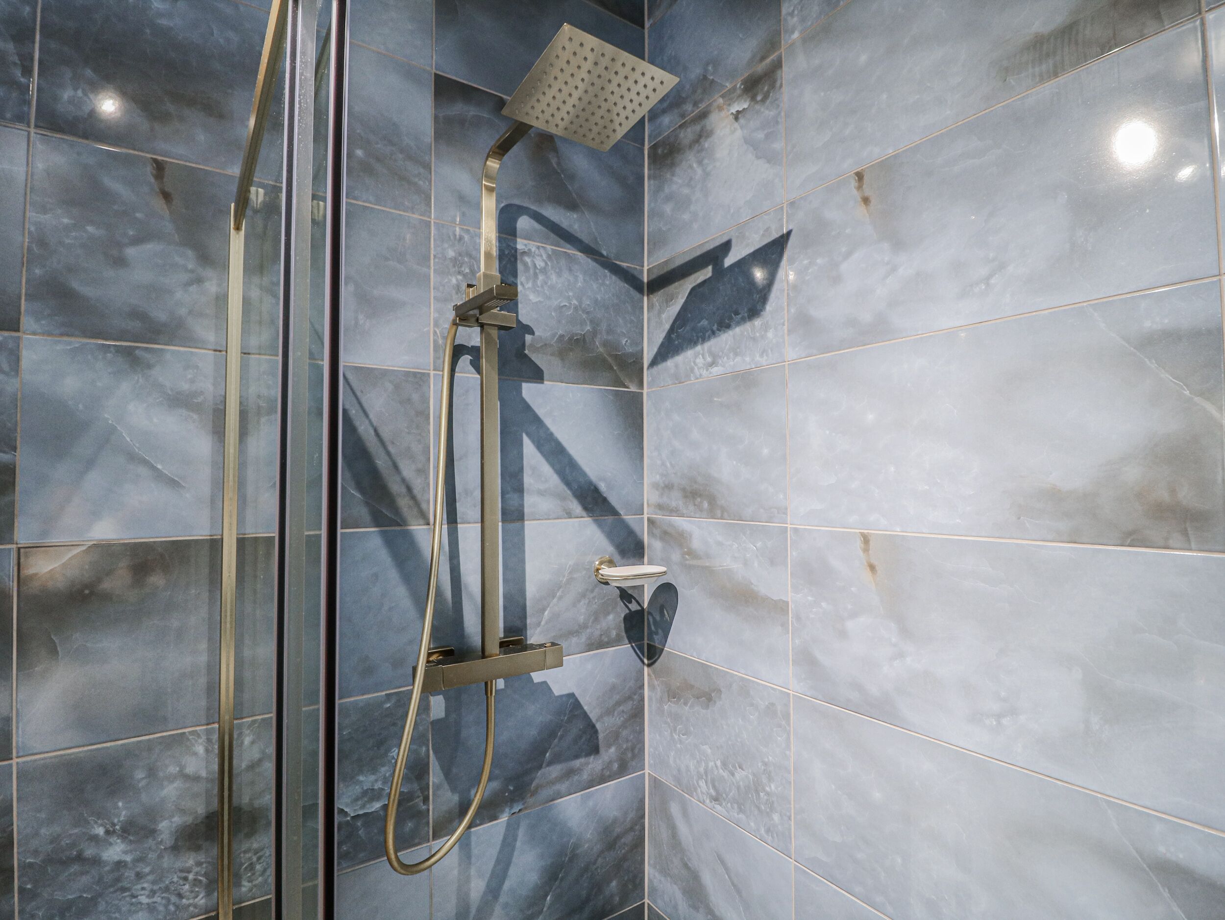 A shower area with a handheld showerhead, a fixed showerhead, and a handheld shower hose.
